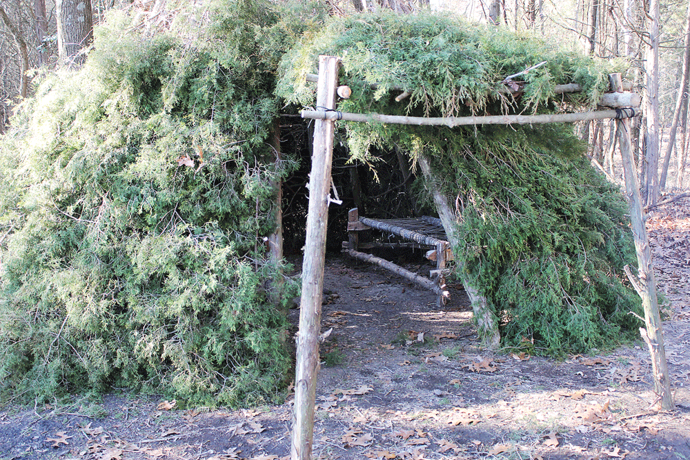 Durch Anheben der Tür und Hinzufügen zu dicken gegabelten Bäumen hat das Wiki jetzt eine kleine Veranda. Ein Kinderbett wird hergestellt, indem ein Zedernholzrahmen gebaut und dazwischen etwa 100 Fuß Paracord fest gewebt wird.