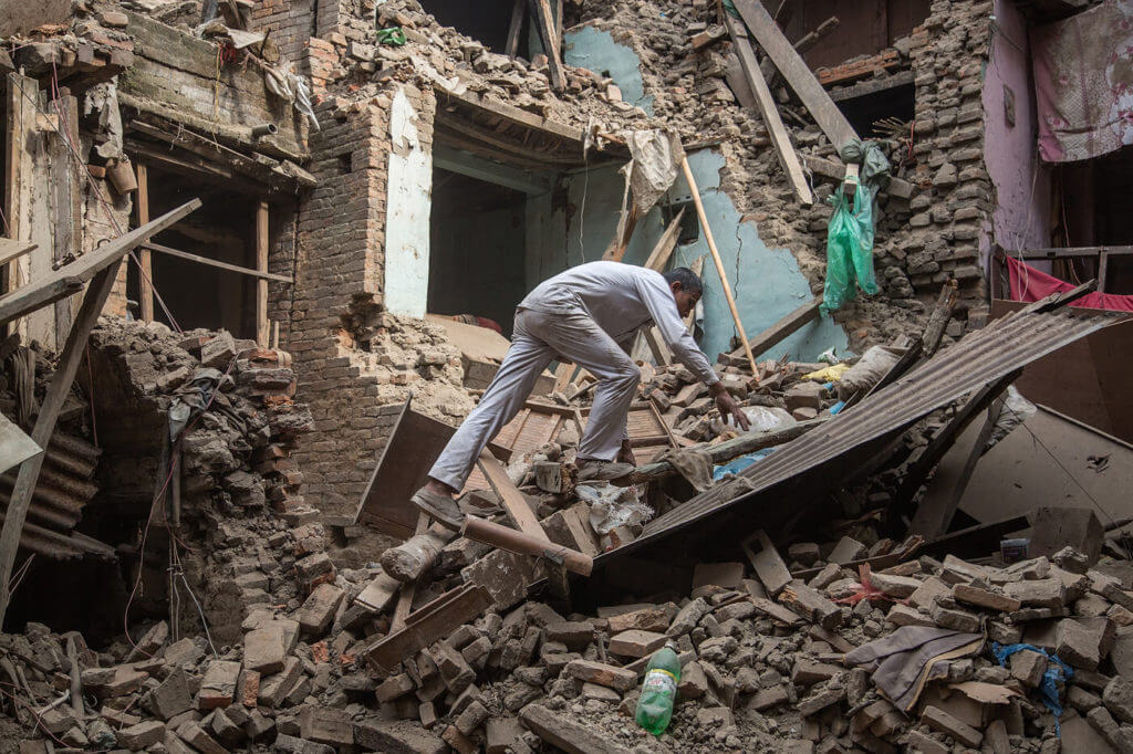 A man searching for survivors in a building destroyed by an Earthquake in Nepal