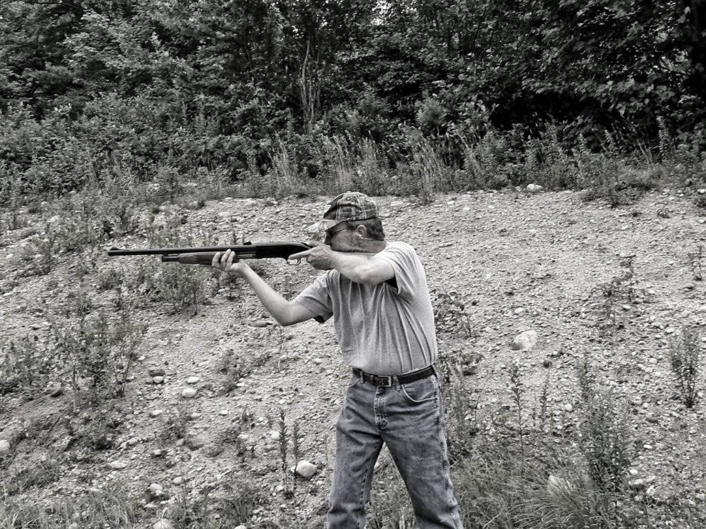 Man aiming shotgun while standing