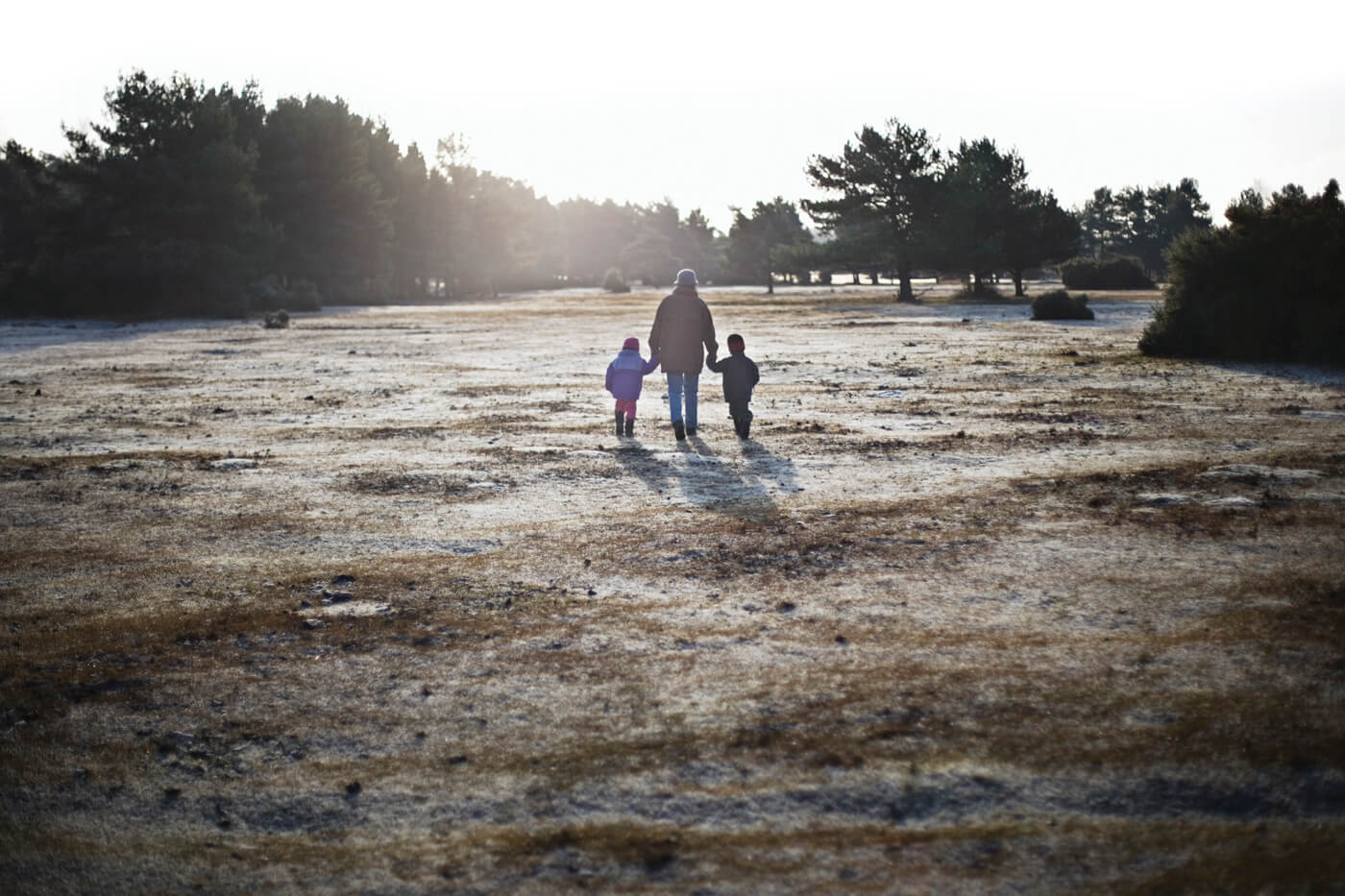 Man walking into the sunset with two children