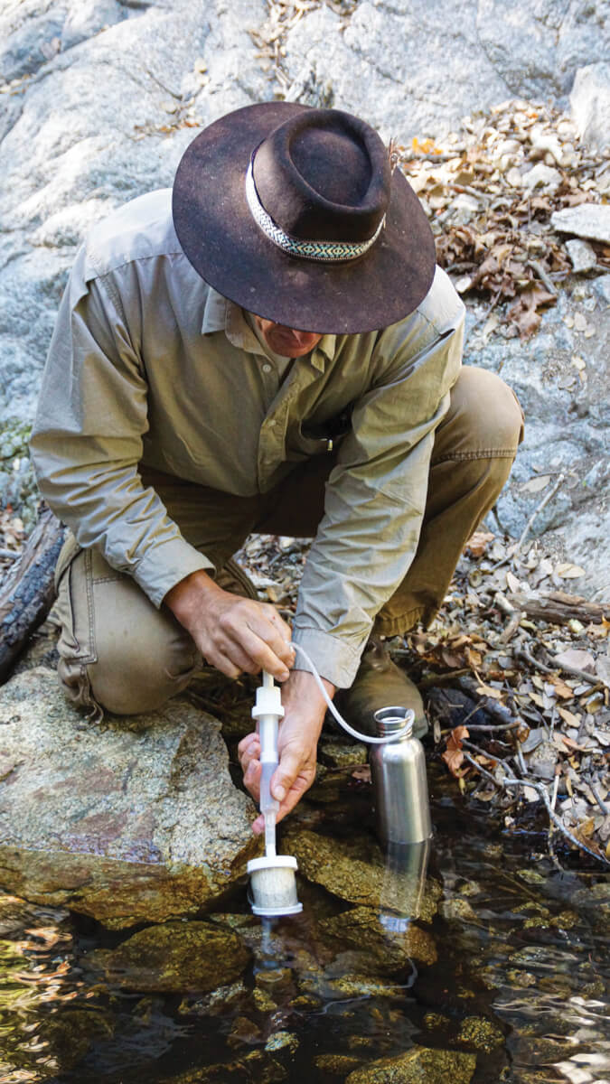 The author demonstrates how to filter stream water with a Timberline water filter.