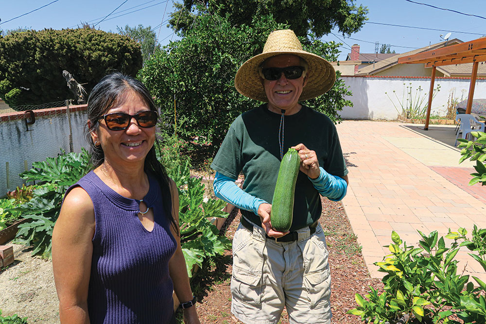 Thuy and Daniel Hyke show a zucchini from their backyard farm.