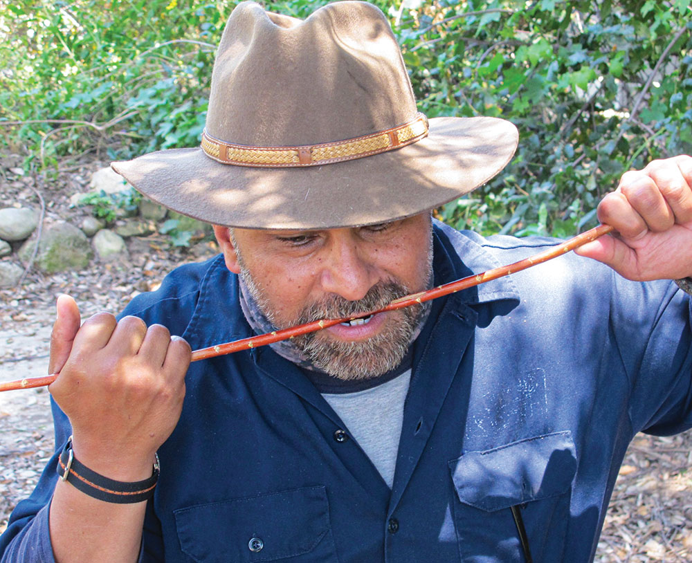 Channeling Larry Dean Olsen, Angelo Cervera straightens an arrow shaft in his mouth. (Photo: Christopher Nyerges, Outdoor Survival Skills, 7th edition)