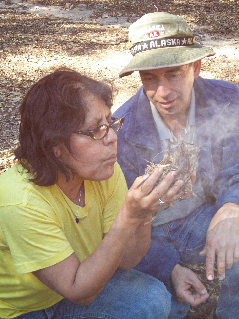 Gary Gonzales helps a student make a fire in the manner of Larry Dean Olsen.