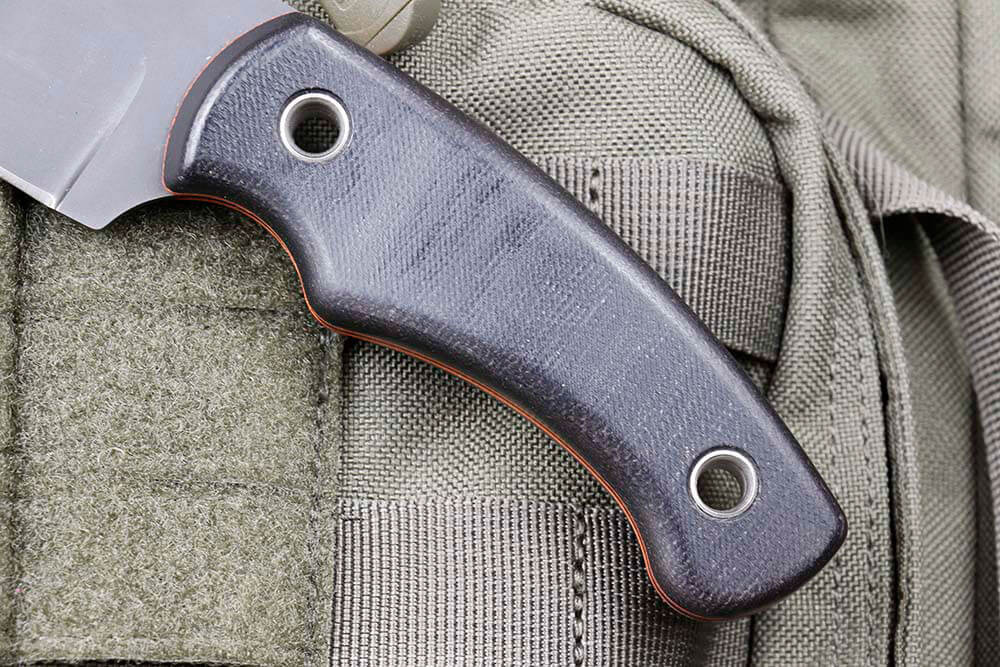 The Nomad features a black canvas Micarta handle with orange G10 liners. 